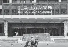  ?? ZHANG KAIXIN / FOR CHINA DAILY ?? A food deliveryma­n rides past the Beijing Stock Exchange.