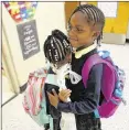  ??  ?? Katelyn Burton, 7, hugs her younger sister Kamryn Howe, 5, goodbye after walking her to her kindergart­en class at Bouie Elementary School.