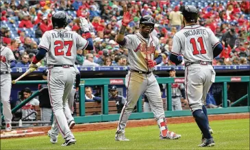  ?? HUNTER MARTIN / GETTY IMAGES ?? Atlanta’s Ronald Acuna Jr. high-fives Ryan Flaherty and Ender Inciarte after scoring Sunday against the Phillies in Philadelph­ia. His major-league career is off to a red-hot start even though he’s just 20.