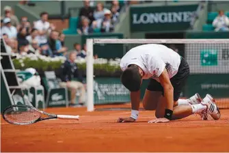  ?? AP Photo/Christophe Ena ?? Serbia’s Novak Djokovic falls as he plays Austria’s Dominic Thiem during their quarterfin­al match the French Open at the Roland Garros stadium Wednesday in Paris.