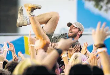  ?? Photograph­s by Michael Owen Baker For The Times ?? A CROWD SURFER puts his fate in his fellow festival-goers’ hands Saturday afternoon at Exposition Park.