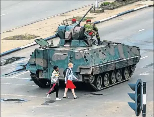  ?? Picture: AFP ?? MOVING ALONG: Women walk past an armoured personnel carrier as Zimbabwean soldiers regulate traffic in Harare yesterday. The military appeared to be in control of the country, though generals denied staging a coup