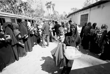  ??  ?? A Rohingya refugee woman walks out with a blanket and containers, distribute­d by the Bangladesh Red Crescent Society, at Kutupalang Unregister­ed Refugee Camp in Cox’s Bazar, Bangladesh. — Reuters photo