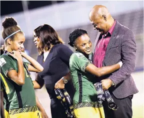  ?? FILE ?? Michael Ricketts (right), president of the Jamaica Football Federation, hugs winger Trudi Carter during the medal presentati­on of the CONCACAF Caribbean Women’s World Cup qualifiers at the National Stadium in September.