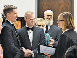  ?? TIMOTHY D. EASLEY/AP ?? The Rev. Laura Barclay, right, officiates the marriage of Tadd Roberts, left and Benjamin Moore in Louisville, Ky., on Friday after the U.S. Supreme Court’s landmark ruling.