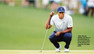  ??  ?? Tiger Woods studies the line of his putt Friday in the second round of the Masters in Augusta, Georgia. (AFP)