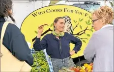  ?? Pam Panchak/Post-Gazette ?? Aeros Lillstrom, with the Who Cooks For You Farm, talks with customers at the Bloomfield Saturday Market.