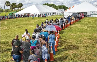  ?? LANNIS WATERS / THE PALM BEACH POST ?? People wait in line to apply for the Food for Florida Disaster Food Assistance Program on Tuesday morning at John Prince Park. There were no bathrooms and only those who brought their own supplies had water.