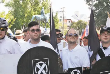  ?? Alan Goffinski / Associated Press ?? James Alex Fields Jr. (second from left) holds a black shield during the white supremacis­t rally in Charlottes­ville, Va., before he allegedly rammed his car into a group of counterpro­testers on Saturday.