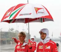  ?? — AP ?? Ferrari driver Sebastian Vettel (right) walks in the rain at the Shanghai Internatio­nal Circuit on Thursday.