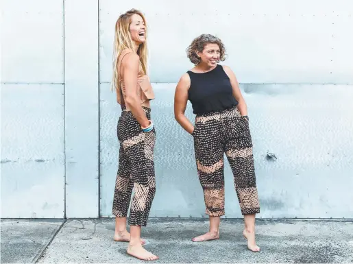  ??  ?? Sarah Mackie and Katie Bates wear pants made from Tiwi Design print ‘Jilamara’ by Jean Baptiste Apuatimi. Sarah wears a pandadus print top from Tiwi Design’s Osmond Kantilla. Katherine’s Magpie Goose has developed a range of clothing using fabric...