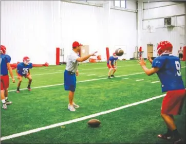  ?? PHOTOS BY WILLIAM HARVEY/THREE RIVERS EDITION ?? Coach Kevin McCarn tosses junior quarterbac­k Clay Harris the ball during a passing drill.