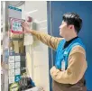  ?? Courtesy of Seoul Metropolit­an Government ?? A Seoul convenienc­e store worker affixes an extreme weather shelter sign at the shop entrance in this undated photo.