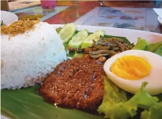  ??  ?? DISH OF THE DAY: ‘Nasi lemak’, a simple but tasty combinatio­n of coconut-flavoured rice, dried anchovies, hard-boiled egg, peanuts and sambal.