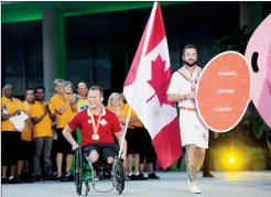  ?? Canadian Press photo ?? Wheelchair rugby player Zak Madell, of Canada, carries the flag during the closing ceremony of the Parapan Am Games in Toronto on Saturday.