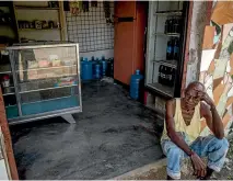  ?? PHOTO: WASHINGTON POST ?? A man rests in front of a store in Barlovento which has not received food since January, forcing people to go to bigger towns or even into Caracas to shop.