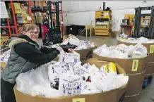  ?? GAVIN YOUNG ?? Jen Little with the Calgary Food Bank helps organize some of the thousands of pounds of food donated during a city-wide food drive. Bins of donated food began arriving at the food bank Saturday.