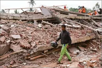  ?? Tatan Syuflana / Associated Press ?? Enjot, 45, who lost his house and a few relatives, walks past the rubble of a building collapsed in Monday's earthquake in Cianjur, West Java, Indonesia, on Tuesday.