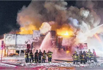  ?? ALEX DIGREGORIO/AP ?? Gas tanker explosion: Emergency personnel work to bring a fire under control after a gasoline tanker overturned and crashed early Wednesday morning in Rockville Centre, New York. Fire officials said the tanker was carrying 9,200 gallons of gas when it crashed into a vacant furniture showroom. The driver and three firefighte­rs who responded were injured.