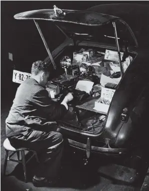  ??  ?? Weegee at the typewriter he kept in the trunk of his Chevrolet, 1942