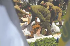  ?? (Shannon Stapleton/Reuters) ?? PEOPLE THROW SOIL into a grave during the funeral of St.-Sgt. Haim Sabach, who was killed in the North, in Bat Yam yesterday.