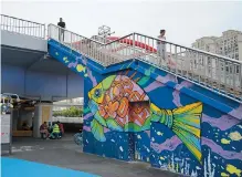  ??  ?? Left: A colorful mural under the Middle
Ring Road in Changning District
Right: A child plays on an installati­on under Kaixuan Road Bridge.