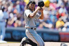  ?? DAVID ZALUBOWSKI/ASSOCIATED PRESS ?? Pittsburgh starter Chris Archer puts on his cap after losing it while trying to field a hit up the middle. Archer allowed two runs in five innings as the Pirates won over Colorado.