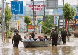  ?? REUTERS PIX ?? (Left) Soldiers evacuating people from a flooded area in Mabi town, Kurashiki, Okayama prefecture, yesterday. (Right) An aerial view of a flooded area in Kurashiki.