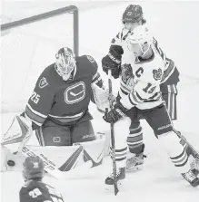  ??  ?? Canucks goalie Jacob Markstrom makes a save as Chicago Blackhawks’ Jonathan Toews, front right, looks for the rebound while being watched by Ben Hutton, back right, during the second period in Vancouver on Saturday. Play was still in progress at press...