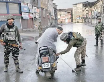  ?? Dar Yasin Associated Press ?? PARAMILITA­RY TROOPS check a bag during a 24-hour curfew in Srinagar, India. Residents pleading to get through checkpoint­s to buy food or go to hospitals were often threatened with beatings by soldiers.