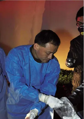  ??  ?? Ma Kaijun, a top forensic expert at the Shanghai Public Security Bureau, and his colleagues gather evidence from a corpse at a murder scene. — Ti Gong