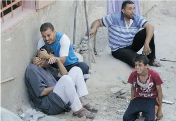  ?? SA I D K H AT I B /A F P/G e tt y I m ag e s ?? Palestinia­ns sit on the street after a deadly Israeli air strike targeted their house Tuesday in the town of Khan Younis in the Gaza Strip. Israeli attacks on Gaza killed 25 people.