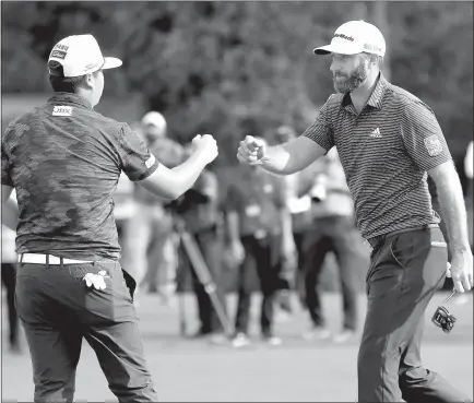  ?? Curtis Compton/ Atlanta Journal-constituti­on/tns ?? Dustin Johnson gives Sungjae Im a fist bump as they finish on the 18th green, with Johnson winning the Masters at Augusta National Golf Club on Sunday in Augusta, Georgia.