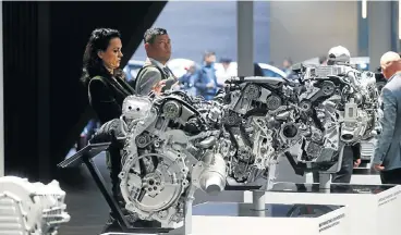  ?? /Reuters ?? Valuation down: People look at BMW engines displayed at the Frankfurt Motor Show in this file photograph. The payoff of developing electric cars is uncertain, as high battery prices will squeeze returns for years.