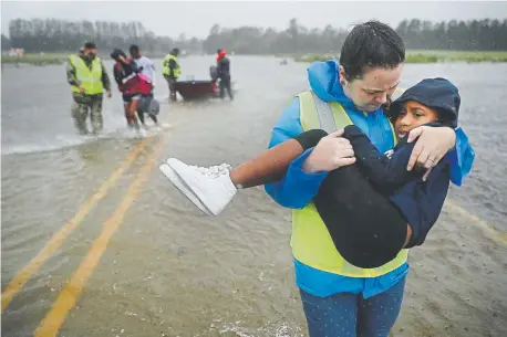  ?? Chip Somodevill­a, Getty Images ?? Amber Hersel of the Civilian Crisis Response Team helps rescue 7yearold Keiyana Cromartie and her family from their flooded home in James City, N.C., on Friday. Florence was downgraded to a tropical storm from a Category 1 hurricane.