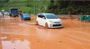  ??  ?? KENDERAAN di Jalan Gua Musang-Lojing terpaksa mengharung­i banjir lumpur.