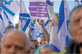  ?? AP PHOTO/OHAD ZWIGENBERG ?? Israelis wave national flags and banners Monday during a protest against plans by Prime Minister Benjamin Netanyahu’s new government to overhaul the judicial system, outside the Knesset, Israel’s parliament­t in Jerusalem.