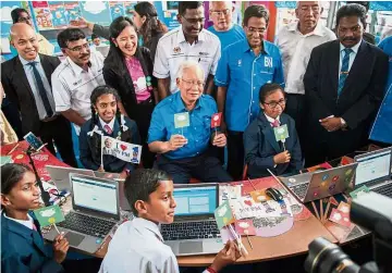  ??  ?? Najib (seated, middle) shares a light moment with the pupils as (standing, first row, from third left) Yeoh, Kamalanath­an, Dr Subramania­m, Noh and Mahdzir (standing, second row) look on.