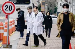  ?? AFP PHOTO ?? MEN OF MEDICINE
Two doctors walk outside the Catholic University of Korea Seoul St. Mary’s Hospital in South Korea’s capital Seoul on Thursday, Feb. 29, 2024.