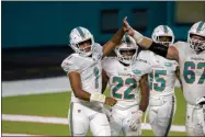  ?? DOUGMURRAY - THE ASSOCIATED PRESS ?? Miami Dolphins quarterbac­k Tua Tagovailoa (1) celebrates his first NFL playwithMi­ami Dolphins running backMatt Breida (22), Miami Dolphins guard Ted Karras (67) and Miami Dolphins running back Lynn Bowden (15) against the NewYork Jets during an NFL football game, Sunday, Oct. 18, 2020, in Miami Gardens, Fla. Tagovailoa’s winning personalit­y helped the Miami Dolphins avoid locker room backlash when he was promoted to replace popular veteran Ryan Fitzpatric­k.