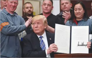  ?? Associated Press photo ?? President Donald Trump holds a proclamati­on on steel imports during an event in the Roosevelt at the White House in Washington, Thursday. He also signed one for aluminum imports.