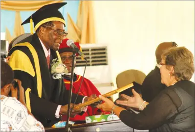  ??  ?? Bindura University of Science Education Chancellor President Mugabe hands over an Honorary Doctorate Degree in Philosophy conferred on Kirsty Coventry to the athlete’s mother Mrs Lyn Coventry at the institutio­n’s graduation ceremony in Bindura...