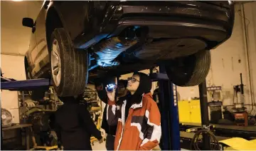  ??  ?? Cristian Hernandez, 18, illuminate­s the underside of a car as he and other students try to find the source of a fluid leak and (right) Excel student Raymond Riley said that taking a vehicle from non-functionin­g to functionin­g “makes you feel good about yourself.” — WP-Bloomberg photos b Sarah L. Voisin