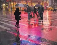  ?? AP PHOTO/ MARK LENNIHANA ?? Shoppers walk in a rainstorm Monday in New York. With people staying home as virus cases surge, Cyber Monday is expected to be the biggest online shopping day yet, bringing in nearly $13 billion in one day.