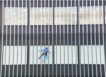  ??  ?? A worker cleans windows on a commercial building at a business district in Tokyo, Japan. Most Japanese companies support loosening the country’s tight immigratio­n system to cope with a severe labour shortage, but they favour skilled workers who can fit into the workplace, not an influx of unskilled labourers, a Reuters poll shows. — Reuters file photo