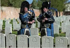  ??  ?? Lament: Pipers play among the war graves in Arras