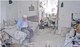  ?? — AFP ?? ARBIN: A Syrian man sits in his damaged house yesterday following an air strike late the previous night on the rebel-held town.