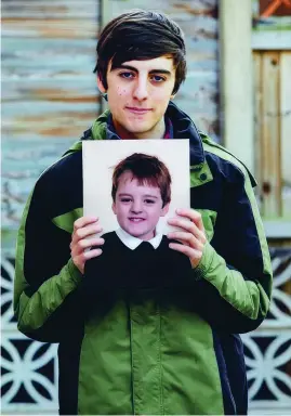  ?? ?? Jake, 22, holding a picture of himself as a child. He reached out to Childline when he was 12 years old