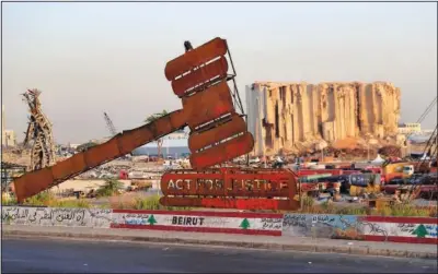  ??  ?? A justice symbol monument is seen Wednesday in front of towering grain silos that were gutted in the massive August 2020 explosion.