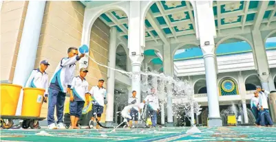  ?? DIPTA WAHYU/JAWA POS ?? BERSIHKAN 1.255 SAJADAH: Peserta apel siaga korona mencuci sajadah di Masjid Al Akbar Surabaya kemarin.